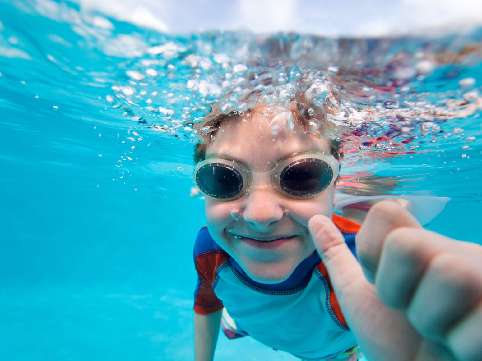 Boy swimming under water in a pool wearing goggles