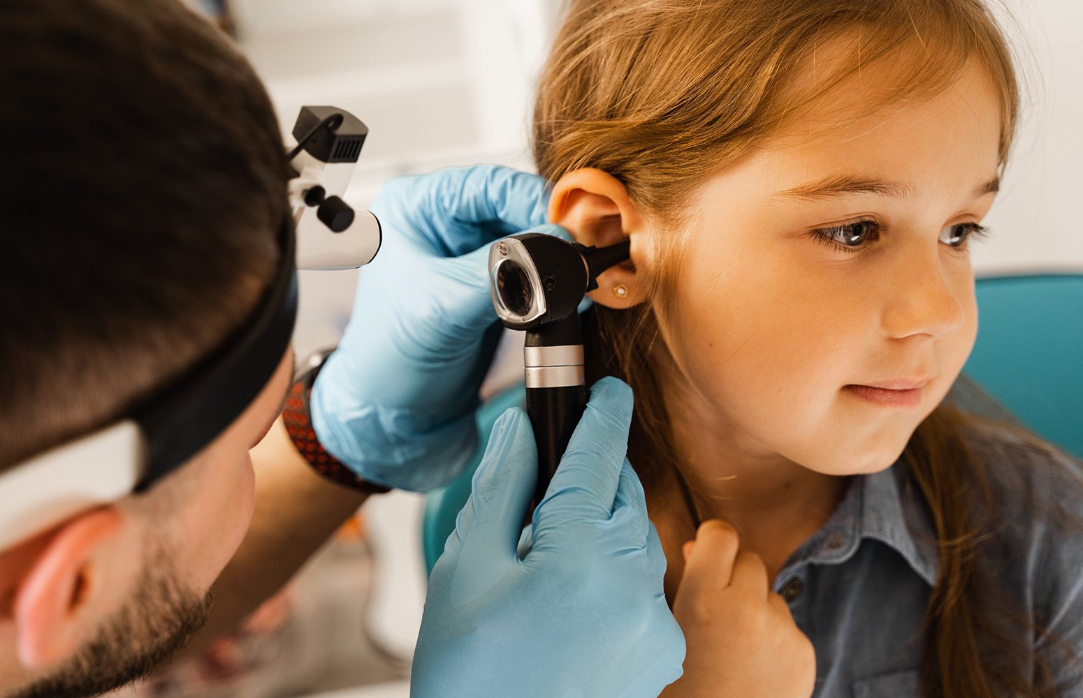 ENT doctor checking childs ears with otoscope