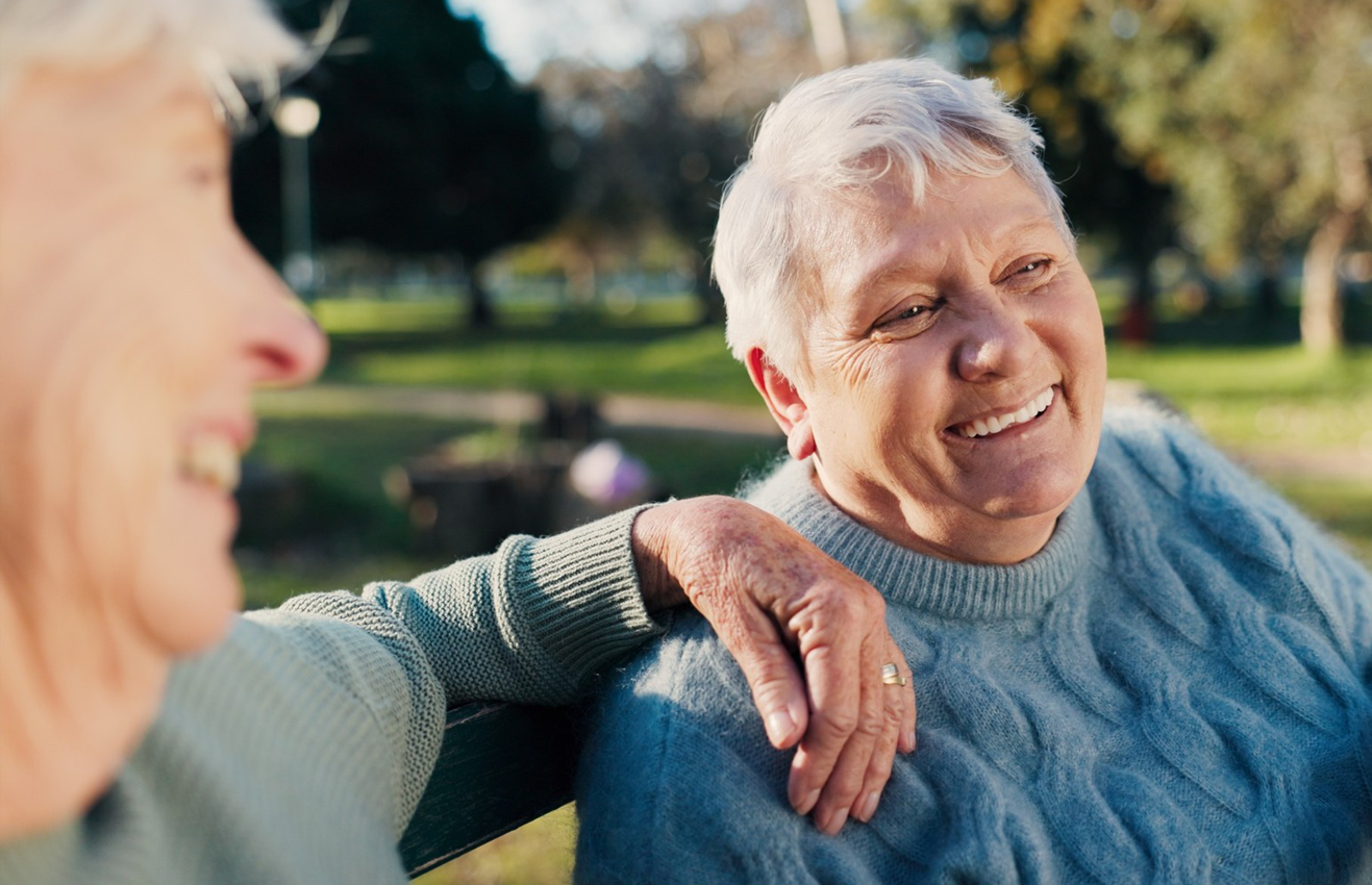 Happy older women sitting in a park, chatting and enjoying nature