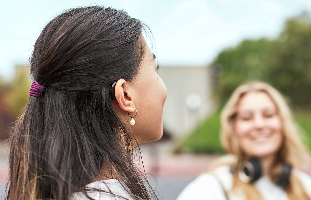 Teenage girl wearing hearing aid out with friend